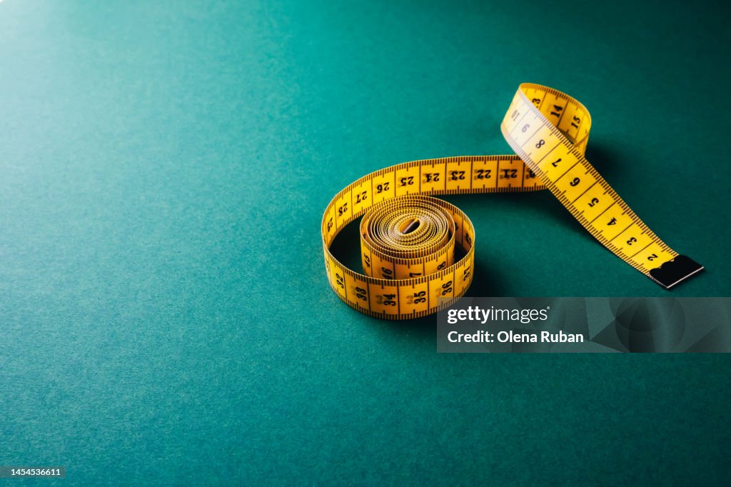 Yellow tailor's tape measure on a dark green board