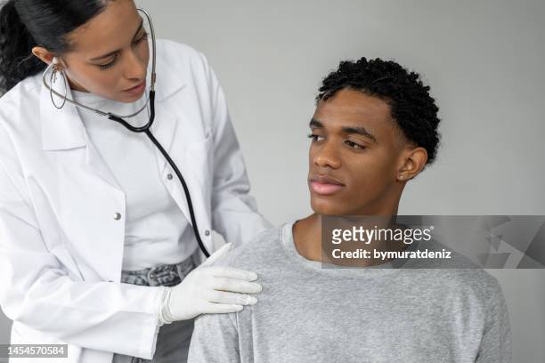 female cardiologist doctor examining lungs of male patient - long term stockfoto's en -beelden