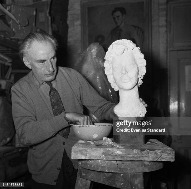 British sculptor Loris Rey working on a plaster model for a sculpture in his studio in his studio on May 30th, 1960. The plaster head is of the...