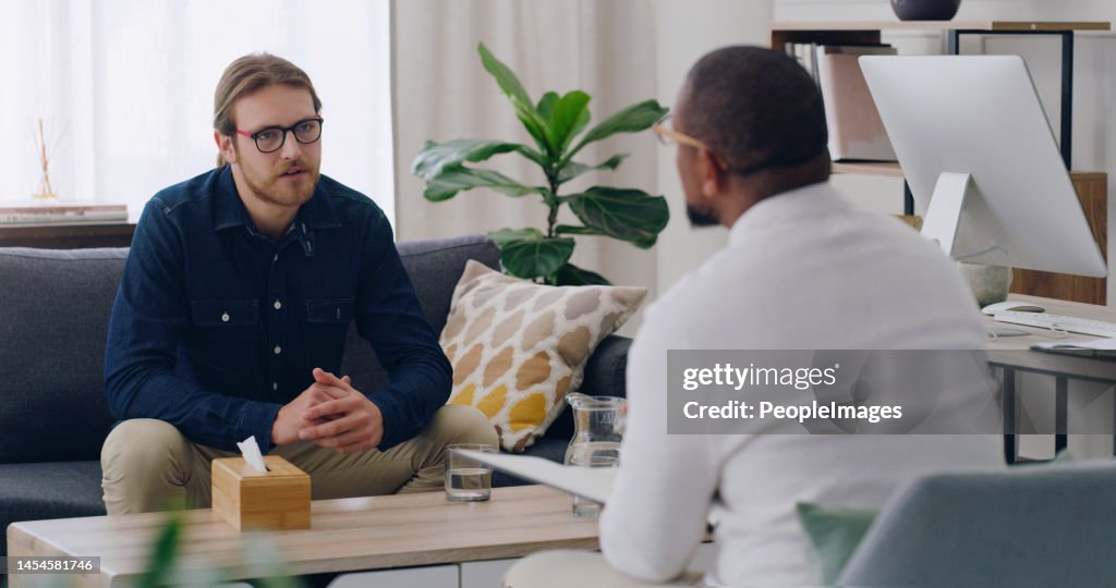 Man, patient or talking to psychologist on sofa in mental health, depression or anxiety counselling therapy. Psychology, stress or wellness counseling therapy help for person in rehabilitation clinic