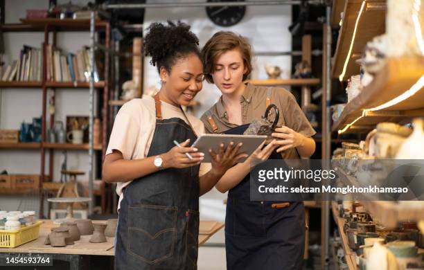 female worker check stock ceramic products on shelf pottery shop - small business stockfoto's en -beelden