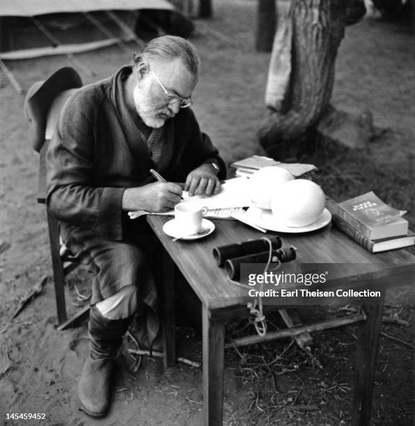 Author Ernest Hemingway writes at a portable table while on a big game hunt in September 1952 in Kenya.