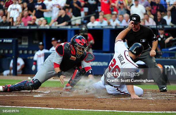 Dan Uggla of the Atlanta Braves slides in to score against Yadier Molina of the St. Louis Cardinals at Turner Field on May 30, 2012 in Atlanta,...