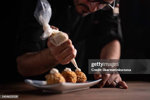 a male chef squeezing cream on meatballs - meatball stock pictures, royalty-free photos & images