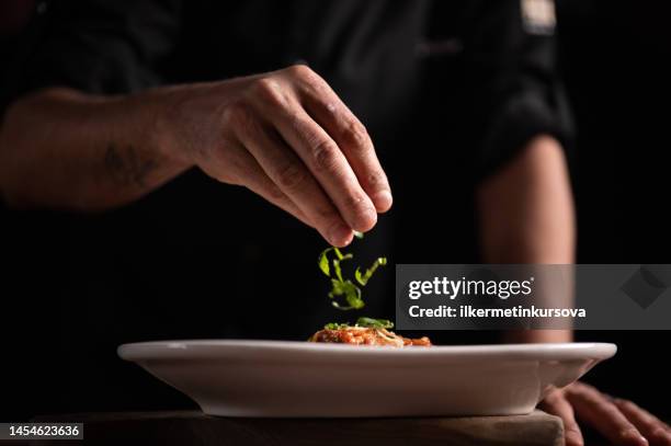 a male chef decorating a plate in a restaurant - serving dish stock pictures, royalty-free photos & images