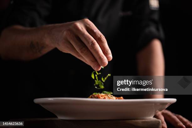 a male chef decorating a plate in a restaurant - chef finishing stock pictures, royalty-free photos & images