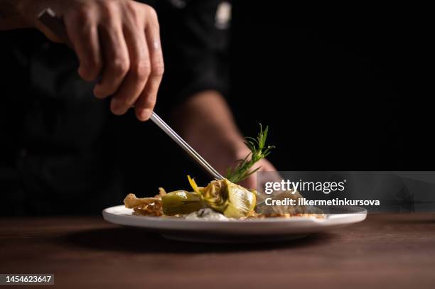 a male chef decorating a plate of artichoke - serving dish stock pictures, royalty-free photos & images