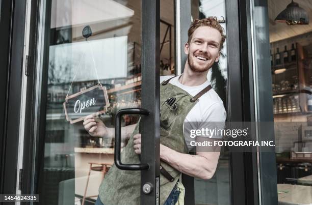 young redhead barman opening the bar - open sign stock pictures, royalty-free photos & images