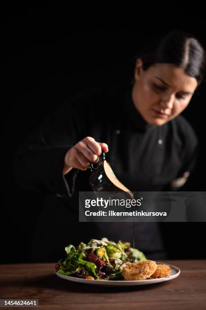 a female chef in restaurant decorating a plate of salad - kokkin stockfoto's en -beelden