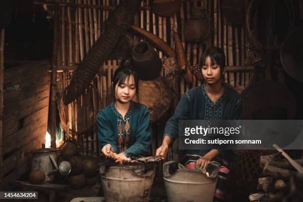 beautiful two thai girls cooking together in the isaan tradition kitchen - gill stock pictures, royalty-free photos & images