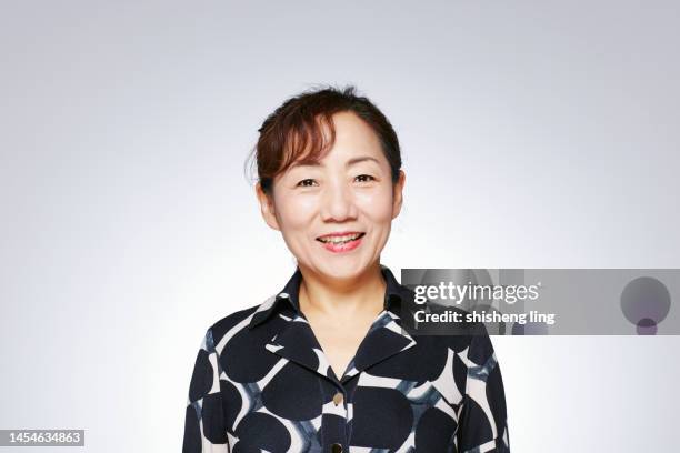 una anciana de asia oriental con una camisa negra mira a la cámara. el estudio filmó sobre un fondo blanco. - east asian ethnicity fotografías e imágenes de stock