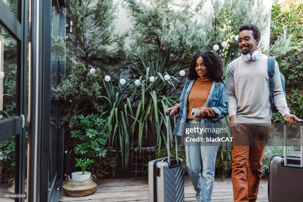 Couple of tourists with suitcases in front of the rental accommodation