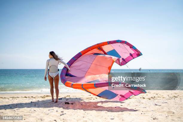 blond-haired woman with kitesurf kite on the beach - kite surf stock-fotos und bilder