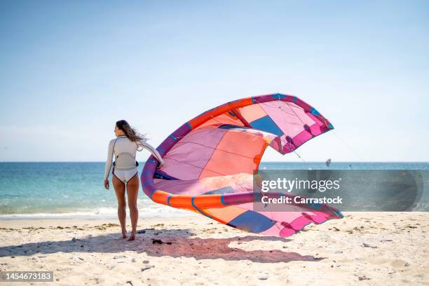 blond-haired woman with kitesurf kite on the beach - kite surfing stock pictures, royalty-free photos & images