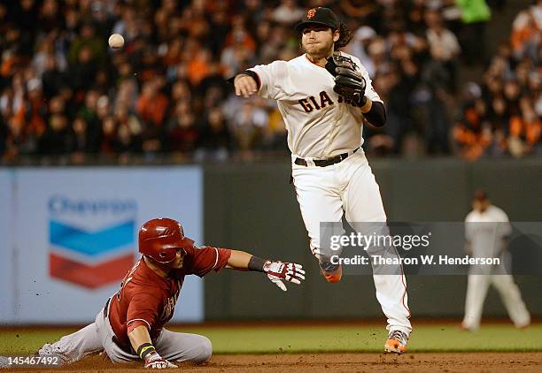 Brandon Crawford of the San Francisco Giants gets his throw off to complete the double-play while avoiding the slide of Gerardo Parra of the Arizona...