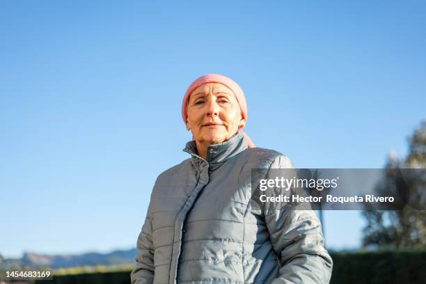 senior caucasian woman with jacket and pink headscarf, cancer and optimism concept - cancer portrait stock-fotos und bilder