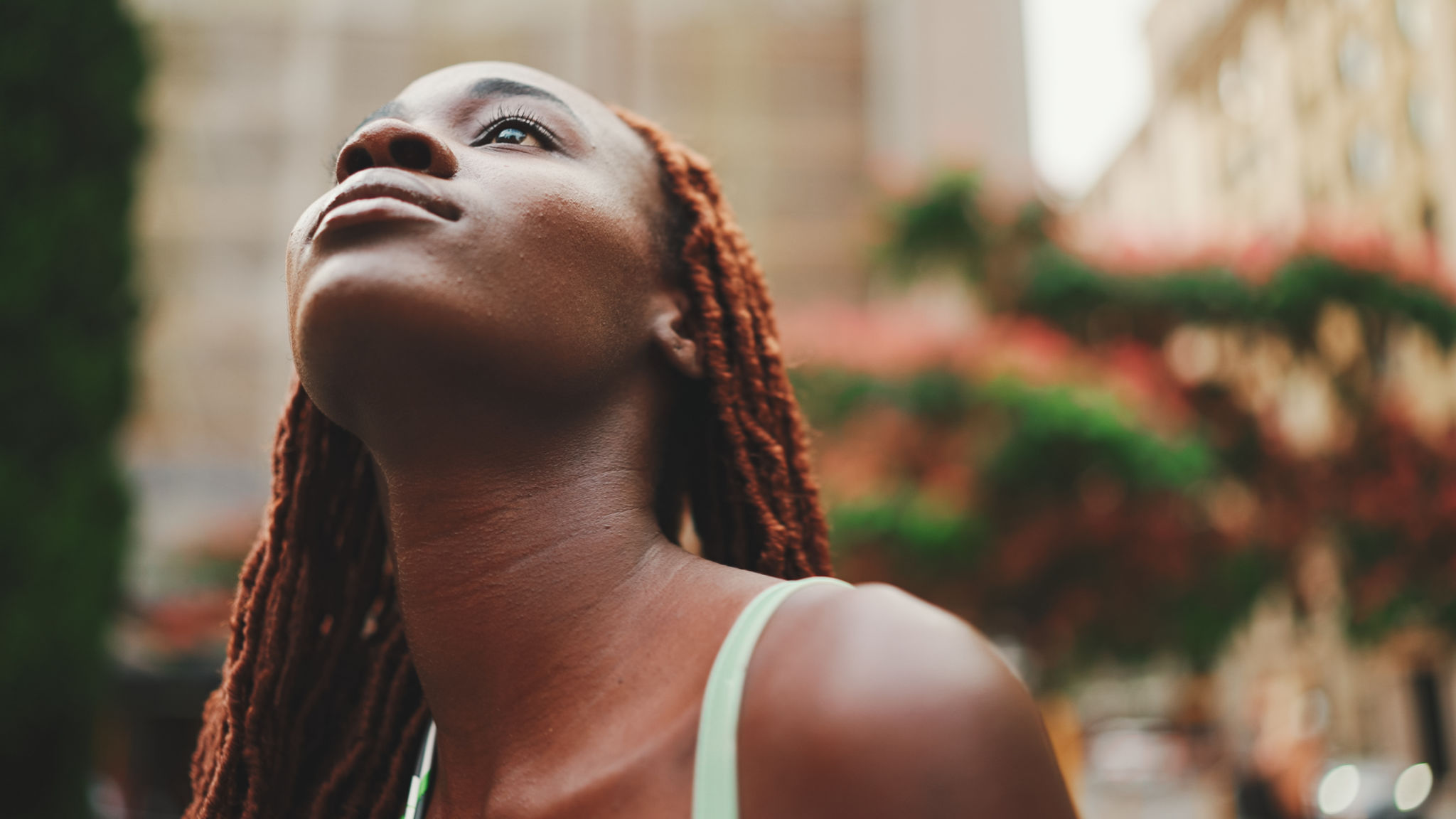 Clouse-up, gorgeous woman with African braids dressed in top walks down the street. Stylish smiling girl looks at the upper floors of buildings. Clouse-up, gorgeous woman with African braids dressed in top walks down the street. Stylish smiling girl looks at the upper floors of buildings.