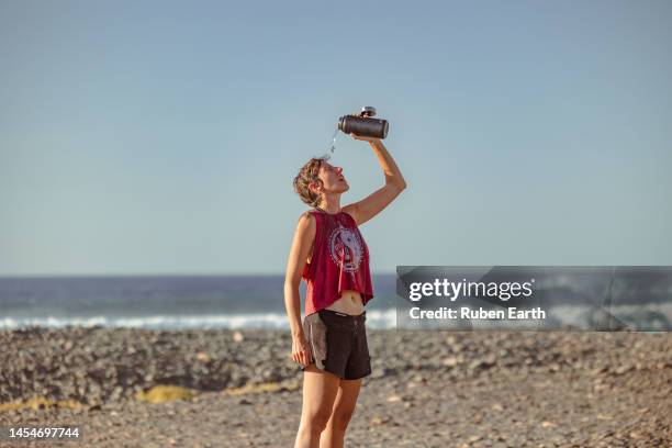 young female runner dehydrated after exercising on the beach in fuerteventura - atlantic islands stock pictures, royalty-free photos & images