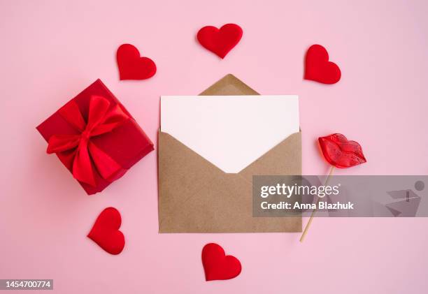 envelope with blank white paper card for copy space, red hearts and candies over pink background. st. valentine's day concept. - valentine card stock pictures, royalty-free photos & images