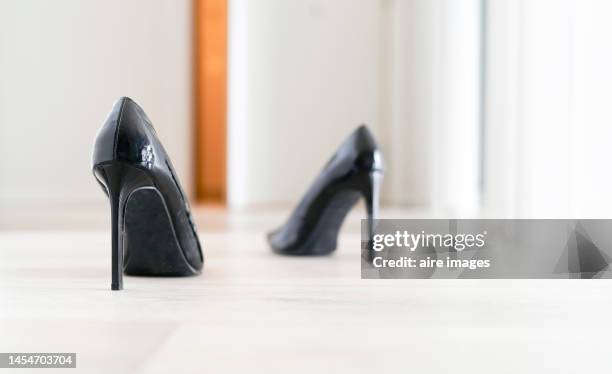 tall black women's shoes placed on the living room floor to be worn after the owner finishes lunch, to continue her work day. - womenswear stock pictures, royalty-free photos & images