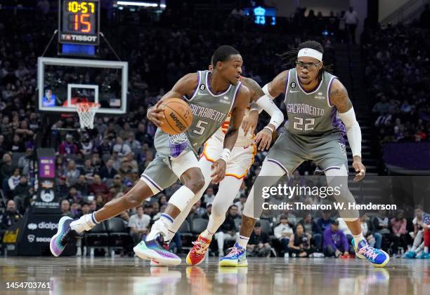 De'Aaron Fox of the Sacramento Kings dribbles around a screen set by Richaun Holmes on Dejounte Murray of the Atlanta Hawks during the first quarter...