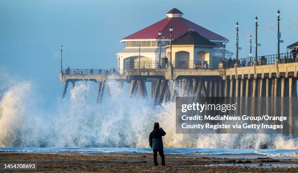 Huntington Beach, CA A beach goer looks on as a large shorebreak wave hits the beach just south of the Huntington Beach Pier early Friday morning,...
