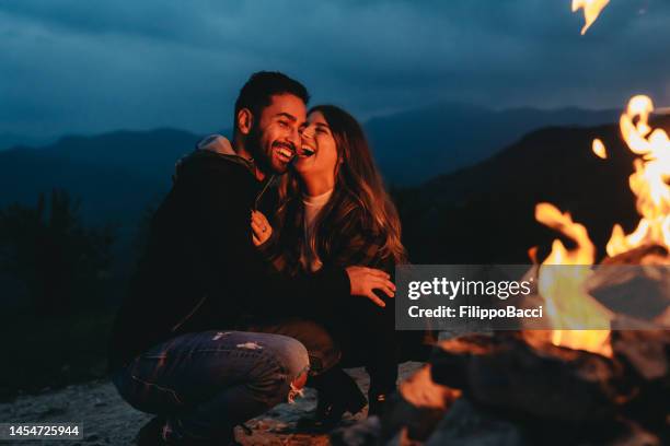 una coppia romantica sta trascorrendo del tempo insieme vicino a un camino all'aperto - bon fire foto e immagini stock