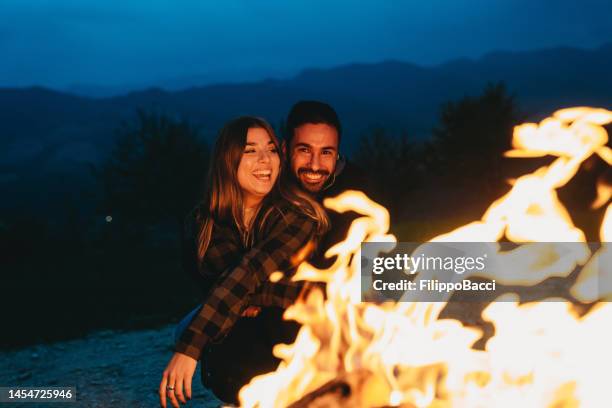 um casal romântico está passando o tempo juntos perto de uma lareira ao ar livre - chalet - fotografias e filmes do acervo