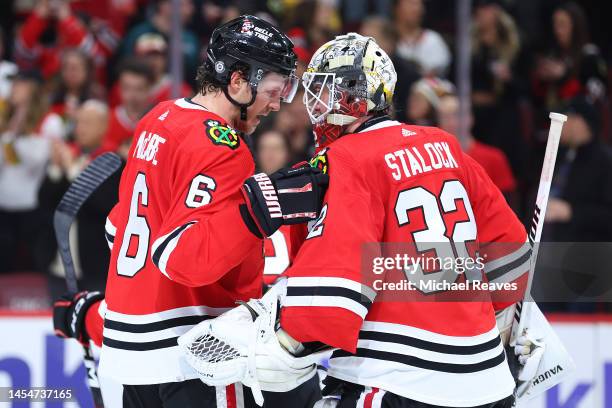 Jake McCabe of the Chicago Blackhawks celebrates with Alex Stalock after defeating the Arizona Coyotes 2-0 at United Center on January 06, 2023 in...