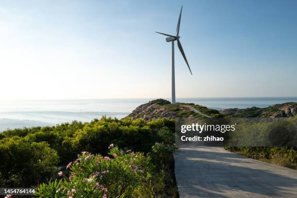 wind turbines on top of seaside mountain - nachhaltiges wirtschaften stock-fotos und bilder