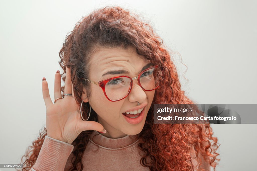 Woman putting hand to her ear