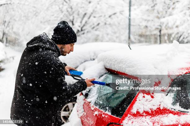 a young man is cleaning ice and snow from a car windshield. - city of spades bildbanksfoton och bilder