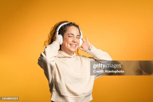 woman listening to music with headphones on yellow background - surroundljud bildbanksfoton och bilder