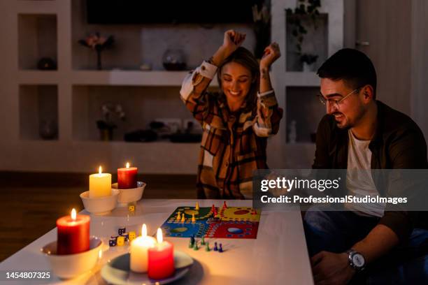 durante una crisi elettrica, un giovane uomo e una donna sono sdraiati a letto e giocano a un gioco di ludo. - candle light foto e immagini stock