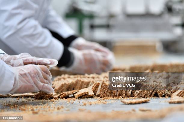 Pastry makers sort out the sliced sesame candy at a sugar workshop on January 6, 2023 in Xiangyang, Hubei Province of China. Pastry makers rush to...