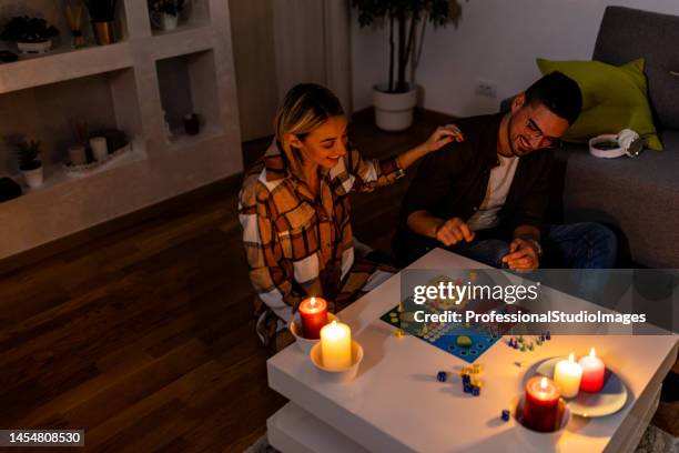 during an energetic crisis, a man and woman are playing a ludo game in the dark with lit candles. - toys house stock pictures, royalty-free photos & images