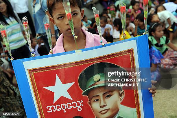 Supporter of Myanmar opposition leader Aung San Suu Kyi holds a portrait of her father and independence hero General Aung San ahead of her arrival at...