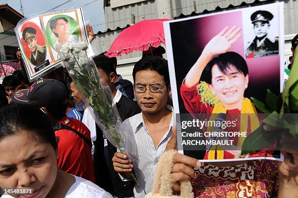 Supporters of Myanmar opposition leader Aung San Suu Kyi hold portraits of her and her father and independence hero General Aung San as they wait for...