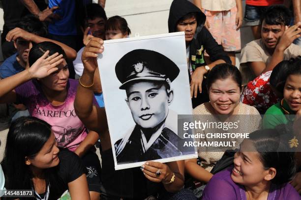 Supporter of Myanmar opposition leader Aung San Suu Kyi holds a portrait of her father and independence hero General Aung San ahead of her arrival at...