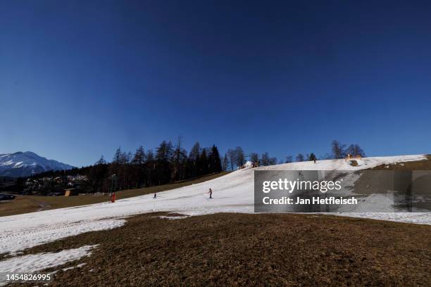 Skiers descend on a slope covered in artificial snow as grass covers the rest of the hill on either side on January 07, 2023 in Seefeld, Austria....