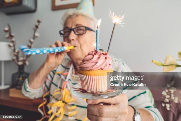 senior woman at home - birthday cupcake stock pictures, royalty-free photos & images