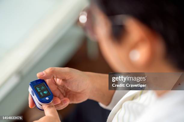 pulse oximeter portable digital device for home health equipment.senior woman measuring oxygen saturation at home. - pulse oximeter stockfoto's en -beelden