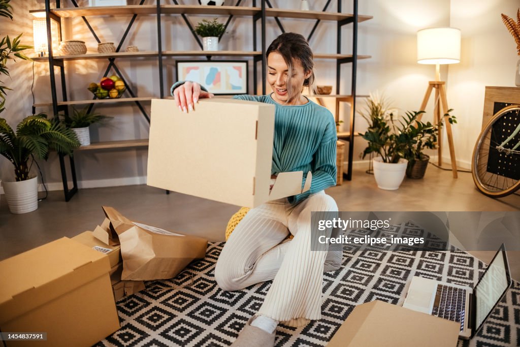 Zufriedene junge Frau, die eine Postzustellung eröffnet