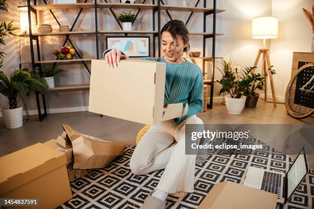 satisfied young woman opening a postal delivery - opening package stock pictures, royalty-free photos & images