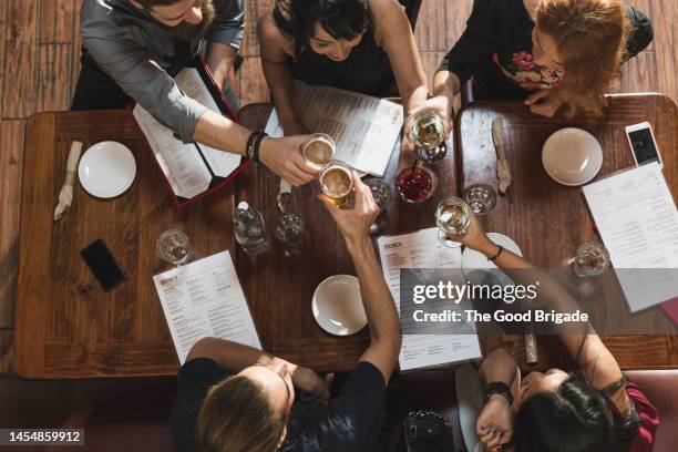 directly above shot of male and female friends toasting drinks in bar - friends toasting above table stock-fotos und bilder