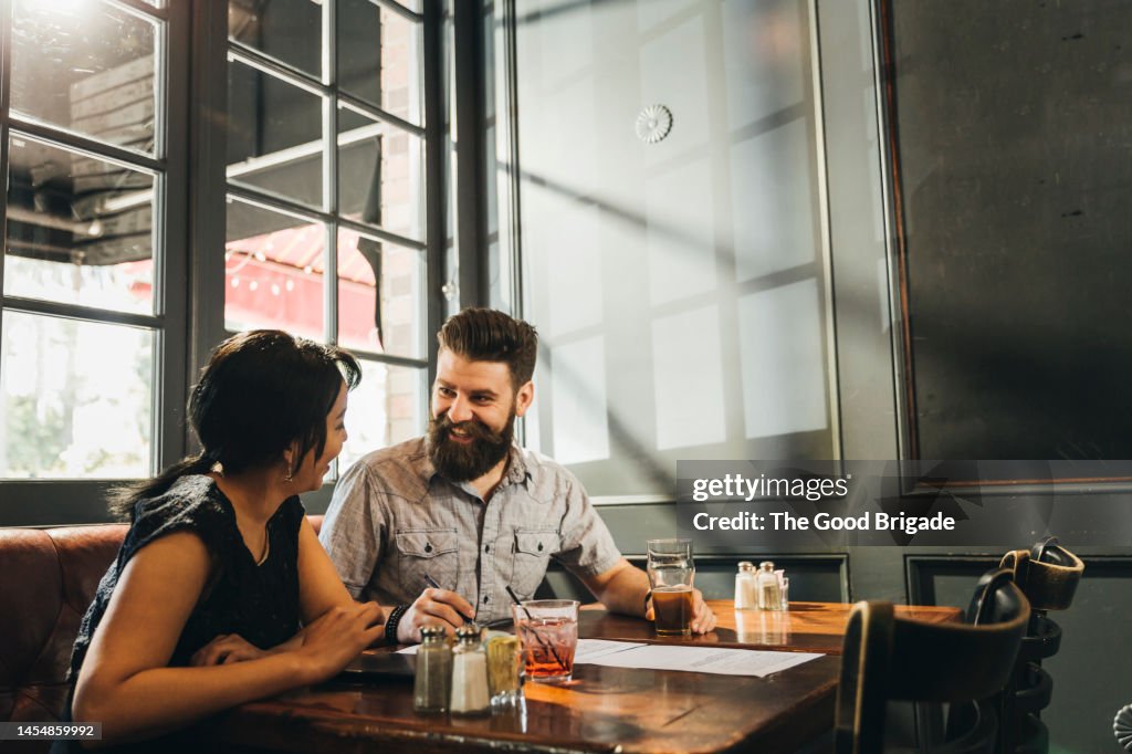 Man talking with female friend while having drink in bar