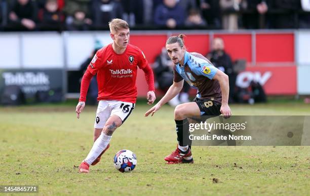 Ethan Galbraith of Salford City moves with the ball watched by Ben Fox of Northampton Town during the Sky Bet League Two between Salford City and...