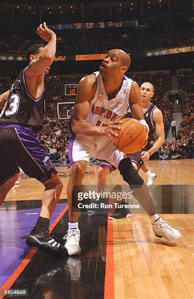 Vince Carter #!5 of the Toronto Raptors looks for the open man along the baseline as he is guarded by his former teammate Doug Christie of the...