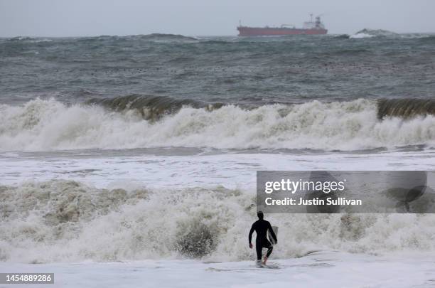 Surfer walks into rough surf as a storm comes in Rodeo Beach on January 07, 2023 in Sausalito, California. The San Francisco Bay Area continues to...
