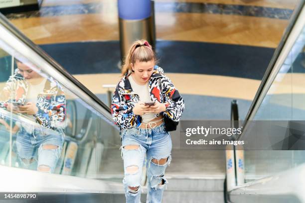 beautiful young smiling blonde girl walking up the escalator to meet her boyfriend on a day out at the mall - ripped jeans stock pictures, royalty-free photos & images